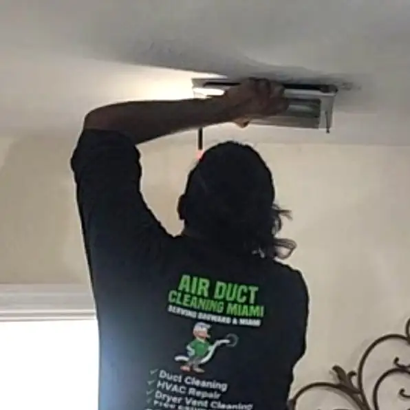 Technician removing AC vent covers from the ceiling for cleaning