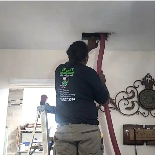 Technician using a HEPA vacuum and Rotobrush to clean air ducts