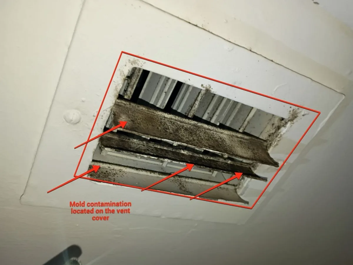 Ceiling supply register in a Miami-Dade home with black mold growth across every louvre and around the duct boot behind it, photographed by a licensed HVAC technician on September 9, 2026